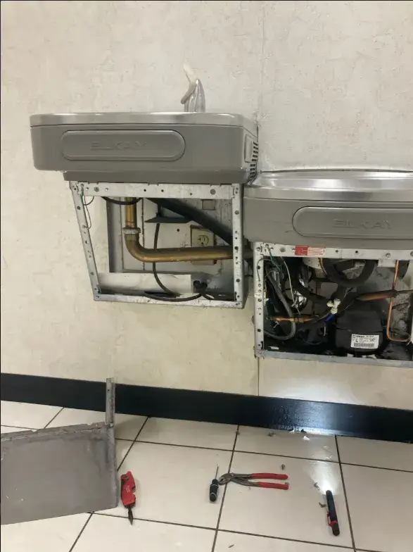 Technician repairing a commercial drinking fountain and bottle filling station