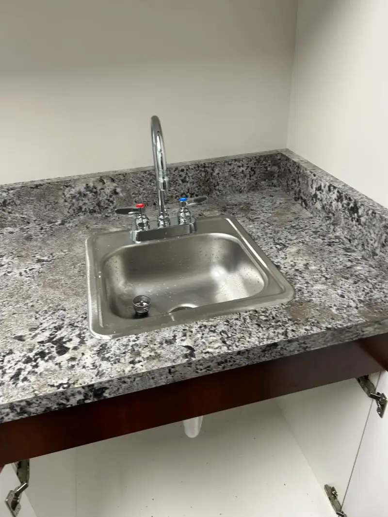 Newly installed stainless steel sink and gooseneck faucet in a granite countertop